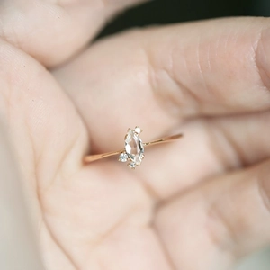 Macro shot of marquise-cut crystal ring in rose gold finish with round diamond accents