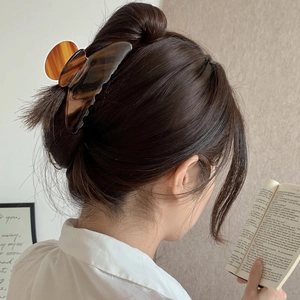Close-up of elegant amber tortoiseshell hair claw clip securing a bun on a woman head