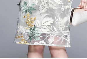 Detailed view of floral embroidery and sparkling sequins on a white mesh dress