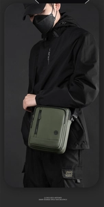 Détail du sac bandoulière vert foncé avec poche zippée avant et bandoulière logo