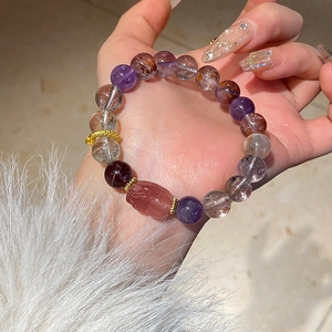 Macro shot of amethyst and multi-gemstone beaded bracelet with golden ring charm