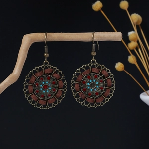 Detail of vintage ethnic drop earrings with hollow patterns on natural wooden branch
