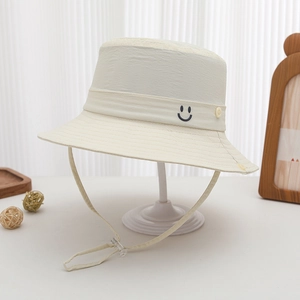 Detail of adjustable windproof rope and embroidered smiley face on a beige sun hat