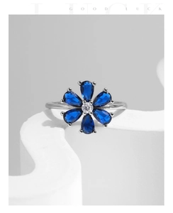 Macro detail of silver flower ring featuring blue drop-shaped stones and a central diamond