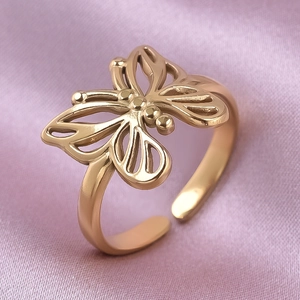 Macro view of gold 304 stainless steel butterfly ring with hollow texture on pink silk