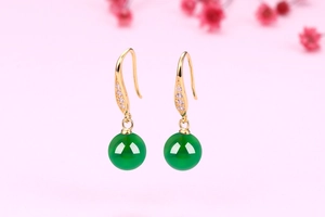 Close-up of green chalcedony drop earrings with gold hooks and sparkling rhinestones