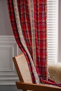 Detail of red and blue plaid cotton curtain with beige lace trim and tassel edges