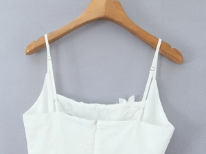 Detailed close-up of white floral embroidery and square neckline on a strap dress