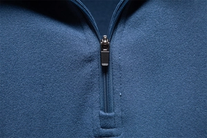 Detail of the high-quality metal zipper and brushed fabric texture on the navy blue sweater