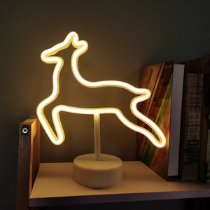 Warm yellow deer neon LED light with white base on a wooden shelf for cozy room decor