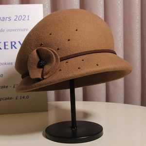 Dettaglio di cappello cloche in lana con fiore decorativo e perline dorate eleganti