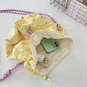 Detailed interior of yellow checkered drawstring bag showing daily storage space with phone
