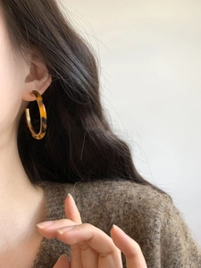 Close-up of tortoise shell resin C-shaped earring on model with polished finish