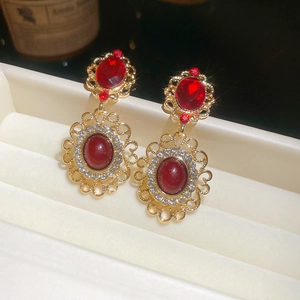 Macro detail of vintage palace style earrings with red stones and gold lace