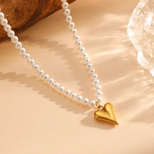 Elegant gold heart pendant on white pearl bead chain necklace with minimalist design