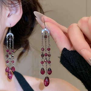 Détail de boucles d'oreilles pampilles en cristal violet avec pierres en goutte