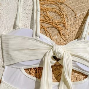 Détail d'un maillot de bain blanc côtelé avec nœud frontal et boucles de sangle réglables