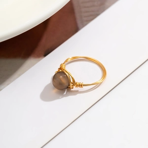 Macro shot of gold wire-wrapped ring featuring a translucent grey-brown stone detail