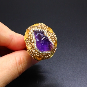 Close-up of vintage gold ring featuring raw purple amethyst and sparkling rhinestones