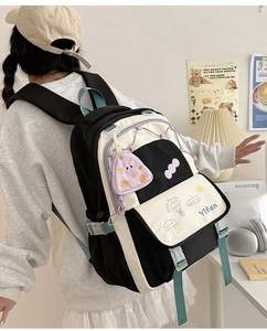 Detail of black and white student backpack with green straps and purple ghost charm