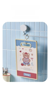 Hanging detail of a cute bear patterned kitchen cutting board on blue tile wall