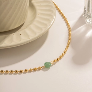 Detail of 18K gold beaded necklace featuring a green oval natural stone pendant