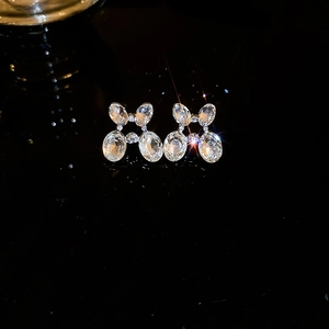 Close-up of elegant silver earrings with oval crystals on a dark reflective surface