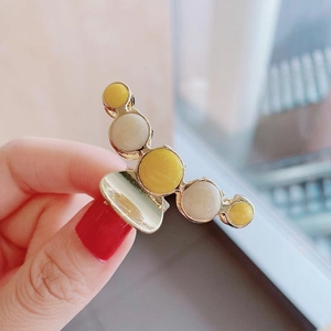 Detailed view of large gold metal hair claw clip with yellow and white pearl bead accents
