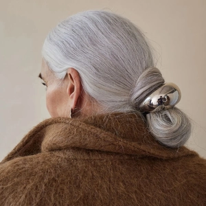 Close-up of minimalist silver metallic hair tie on ponytail with luxury mirror finish