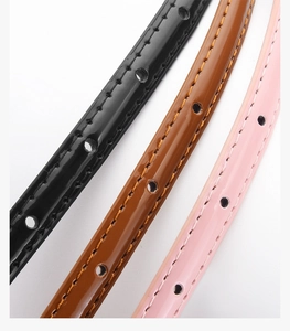 Detailed close-up of slim candy-colored belts in black, brown and pink with stitching
