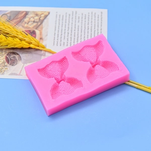 Pink bow-shaped silicone mold for chocolate and fondant cake decoration on blue background