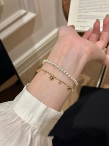 Close-up of double-layer bracelet with pearls and heart star charms on a model's wrist