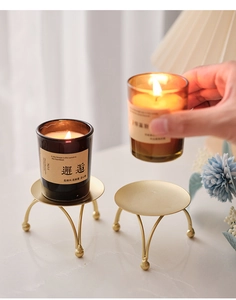 Detail of a minimalist gold metal candle holder tray with spherical support feet