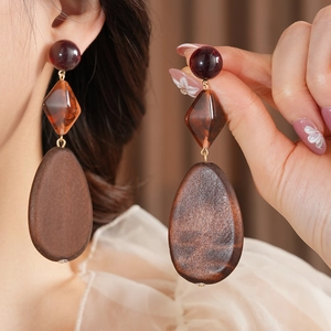 Detailed close-up of retro triple-layered earrings with amber resin and wood teardrop