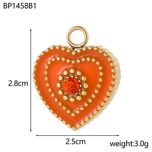 Detail of an orange enamel heart pendant with golden beads and a centered rhinestone