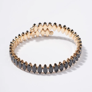 Elegant gold spiral bracelet with black marquise cut zircons on a white background
