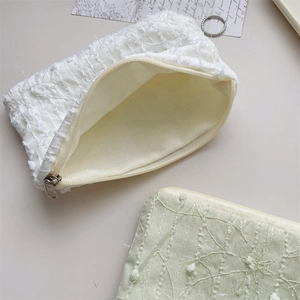 Detailed close-up of 3D chiffon floral texture on cream and green cosmetic bags