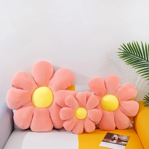 Set of pink flower shaped plush cushions in various sizes on a sofa with green plants