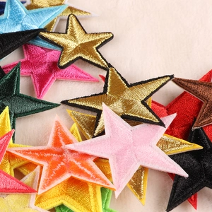 Colorful star-shaped strawberry embroidery patches stacked on soft beige velvet fabric