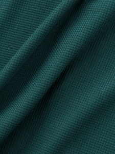 Vue macro du tissu en maille gaufrée vert foncé montrant la texture et le drapé du set