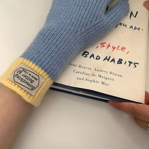 Detailed close-up of blue and yellow knit gloves with ribbed cuffs and brand woven label