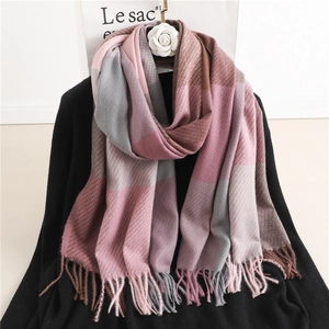Detail of pink and grey plaid scarf with tassels draped on a classic black sweater