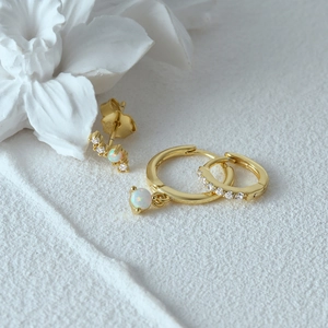Detail of three-piece gold evil eye earring set featuring opal and zircon stones