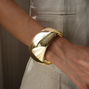 Close-up of wide polished gold cuff bracelet with high mirror finish on model wrist