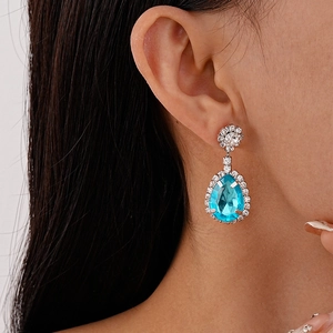 Close-up of teardrop earring with bright blue pear-cut stone and sparkling diamonds