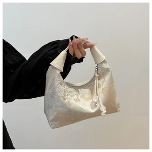 Detailed close-up of traditional floral embroidery and satin texture on a Chinese style handbag