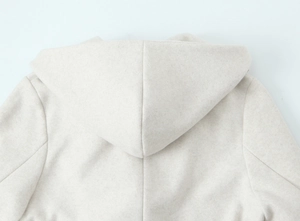 Detailed close-up of soft oatmeal cashmere hooded coat showing hood and shoulder seams