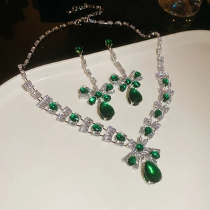 Detail view of emerald green teardrop necklace and earrings set on a white ceramic plate