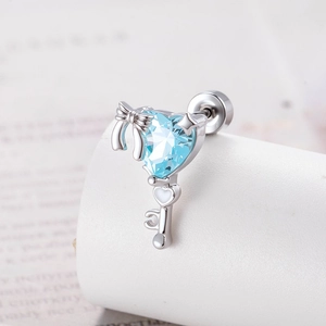 Silver bow heart zircon key earring stud on white minimalist jewelry display stand