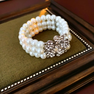 Detail of multi-layer white pearl bracelet with a sparkling diamond clover clasp
